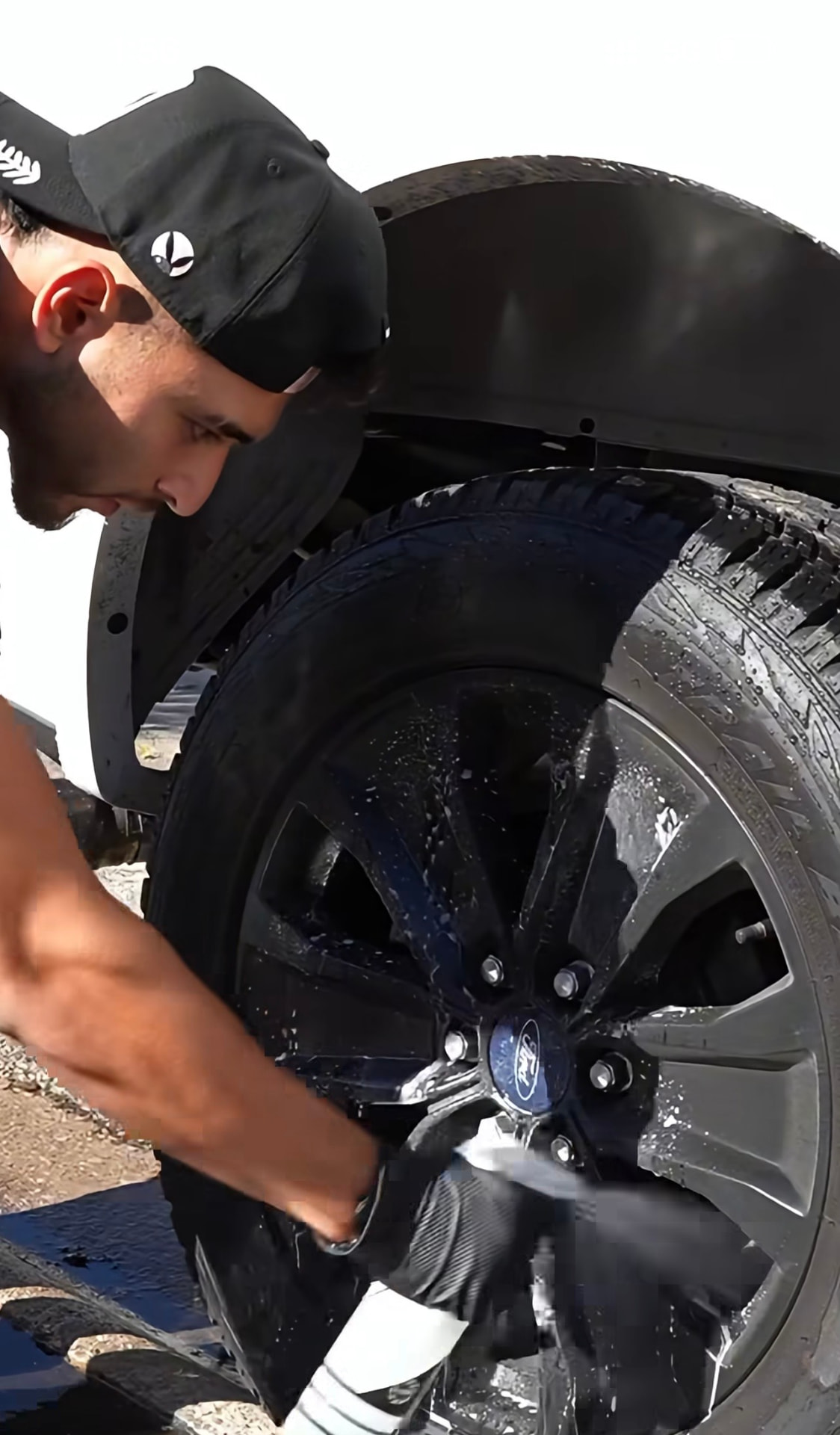 Empire Detailing technician pressure-rinsing a black alloy wheel on a truck